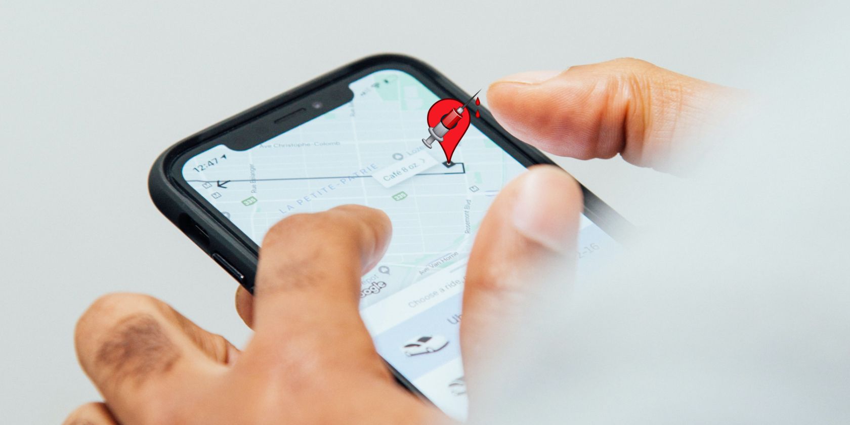 A close-up showing someone ordering an Uber ride on the app, with a vaccination site location balloon.