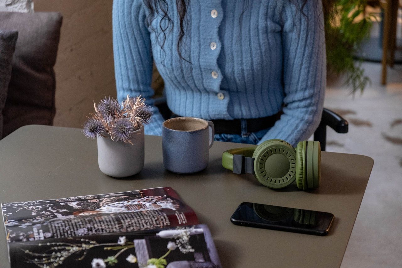 Woman in Blue at Coffe Table with Assorted Items