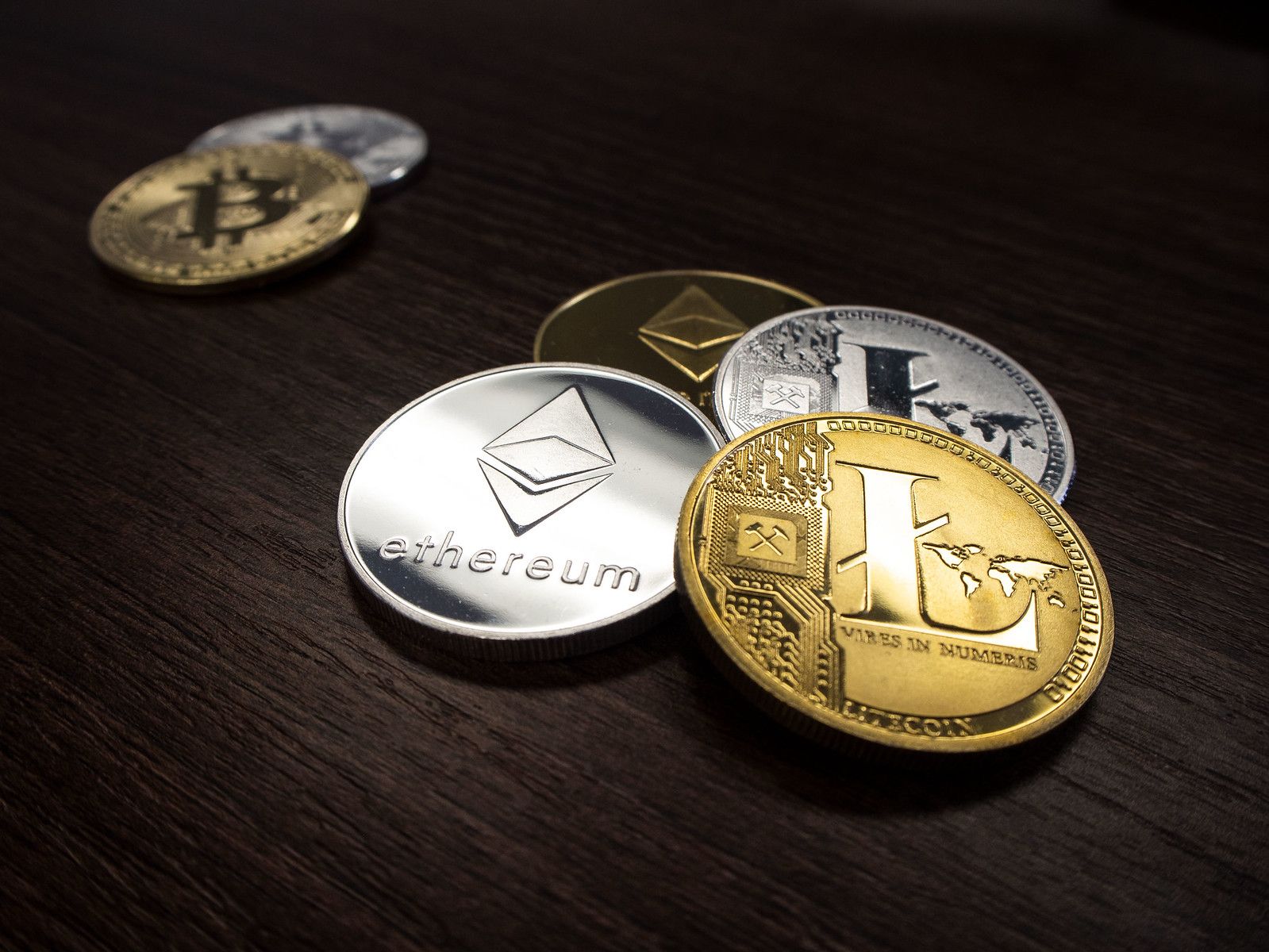 Ethereum, Ripple, and Litecoin placed on a table separate from Bitcoin