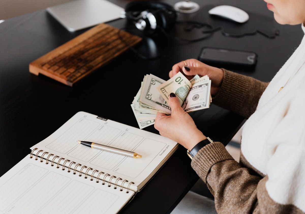 woman with money, journal, phone, assorted items