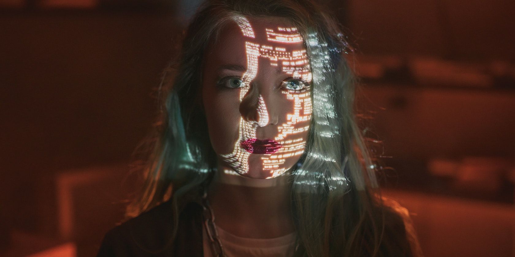 image of a blue-haired woman standing in the dark with numbers and codes projected onto her face