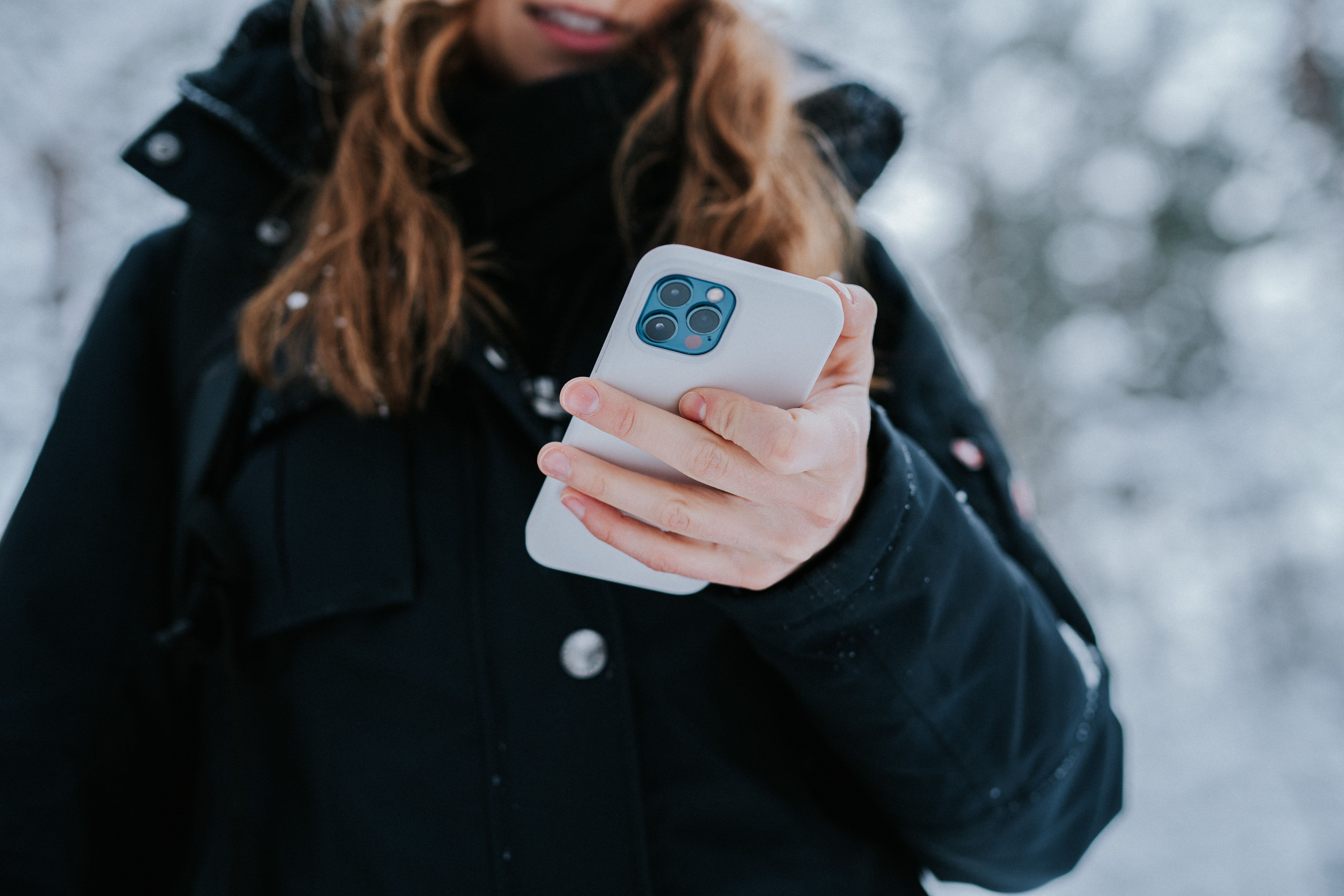 woman holding iphone in jacket