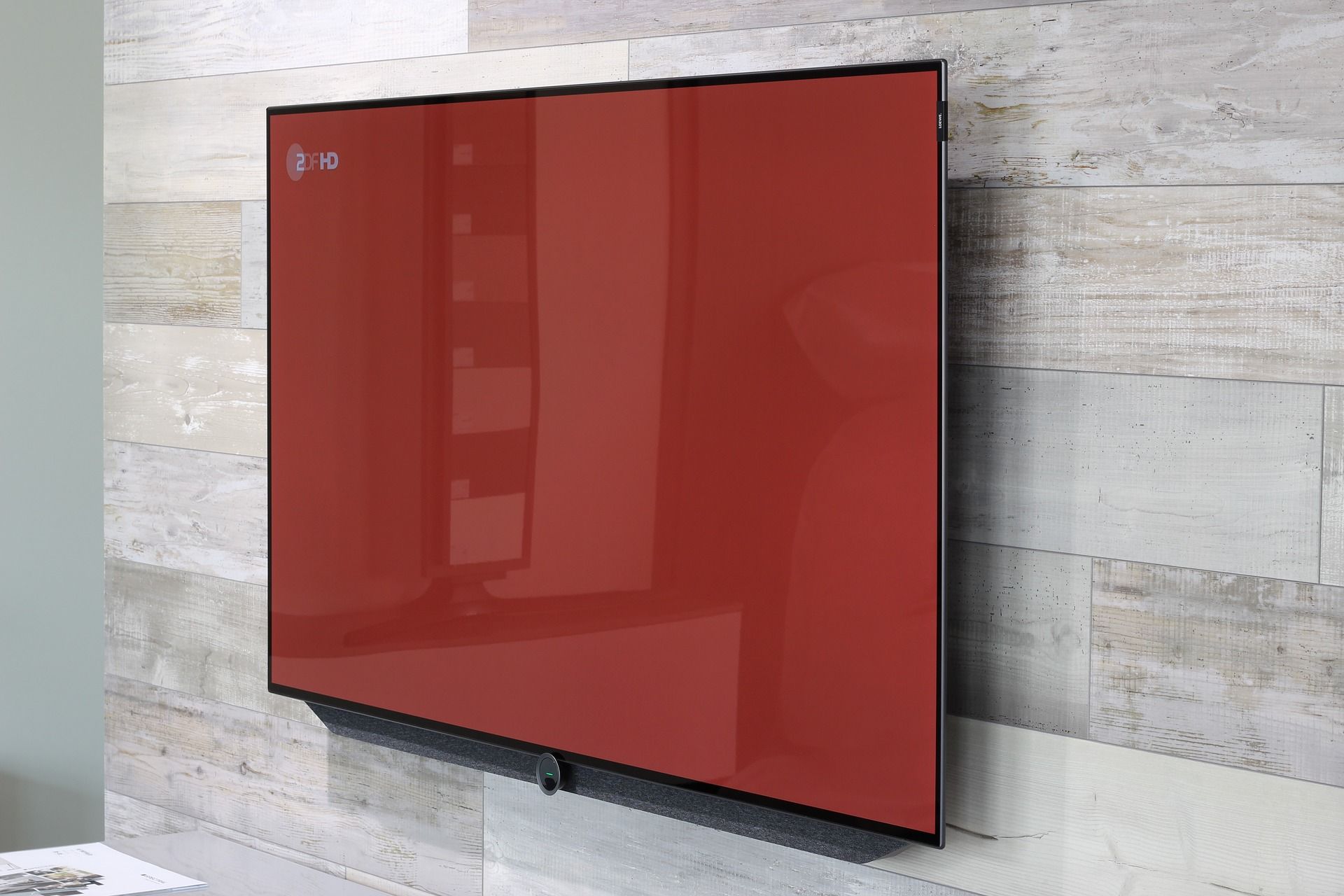 large television with red display mounted on wooden wall