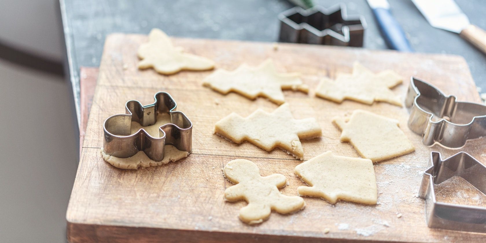 A photograph of metal cookie cutters with several shapes cut out of dough