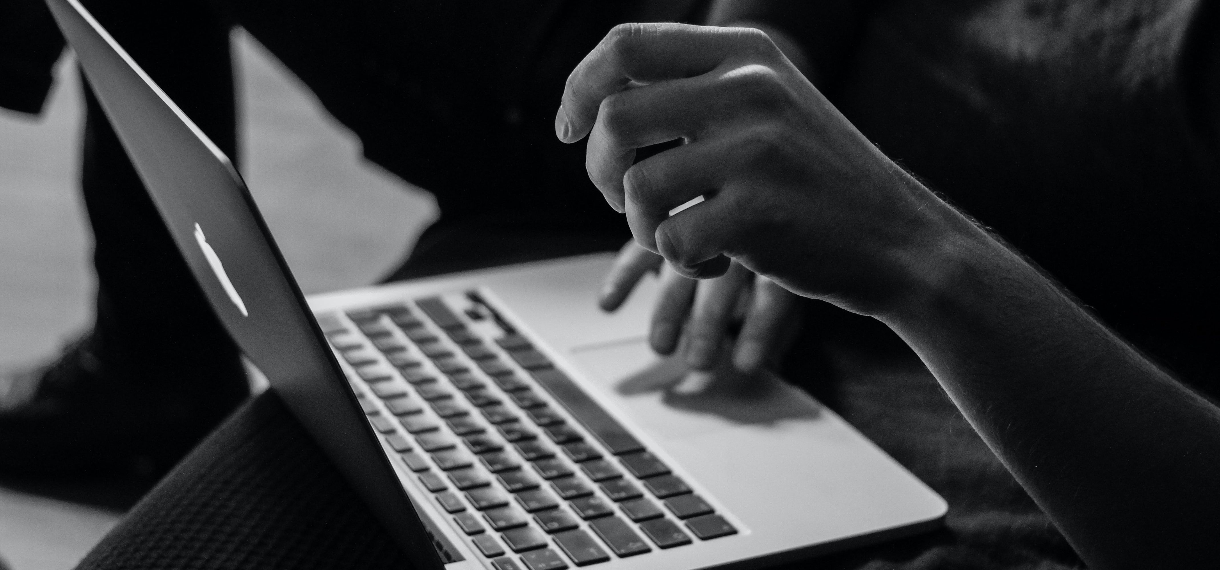 Hands browsing on a laptop.