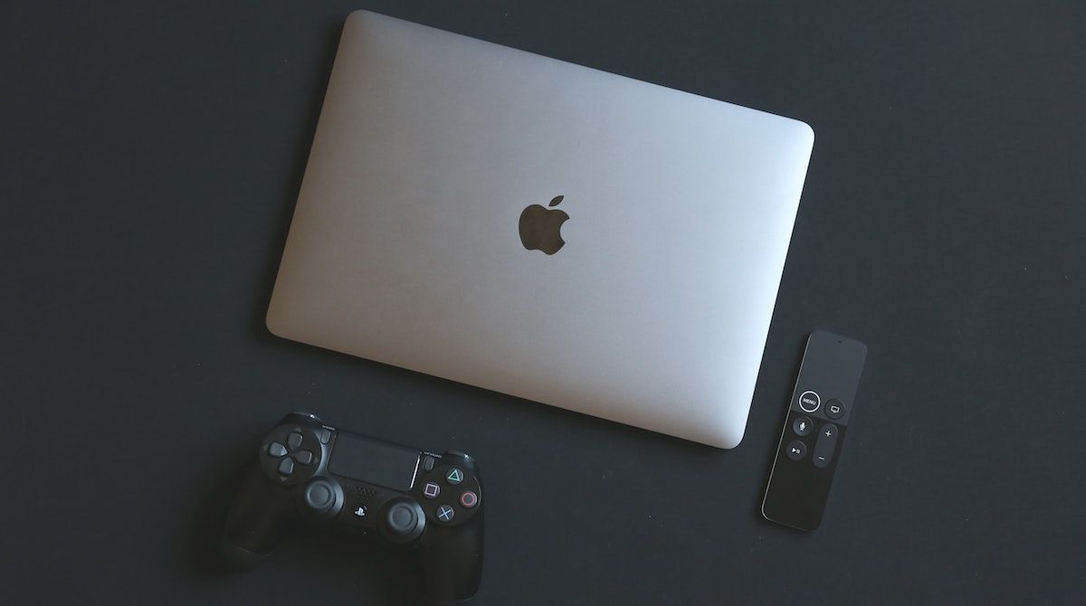 A PS4 controller next to a MacBook and a mini controller