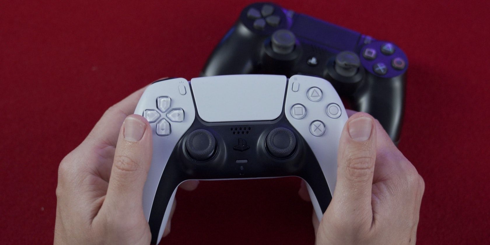 A person holding a PS5 controller with a PS4 controller in the background