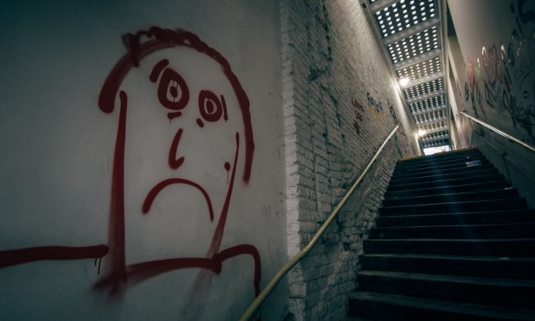 sad man graffiti at the bottom of a staircase