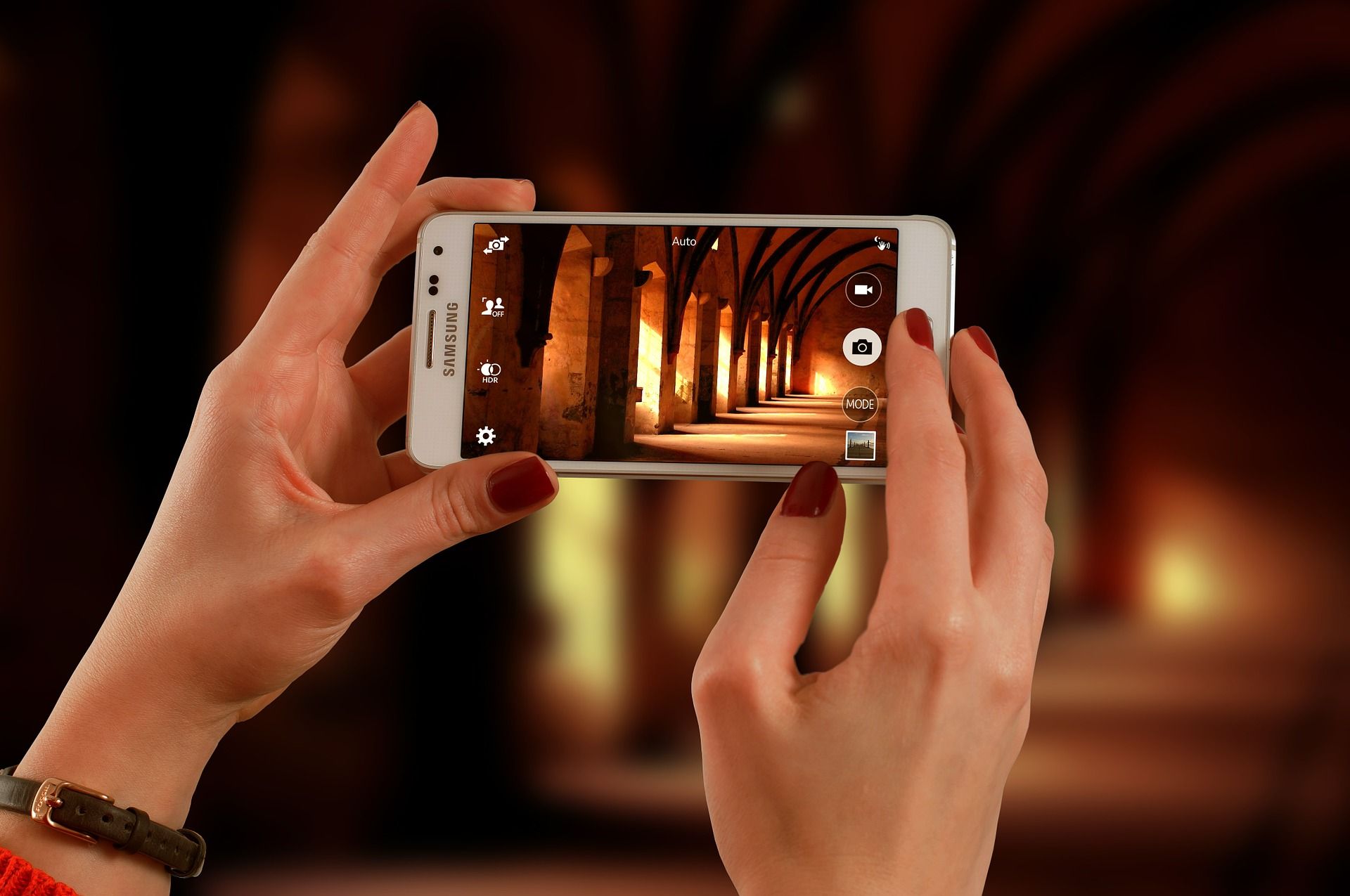 Two hands holding a smartphone in dark hall