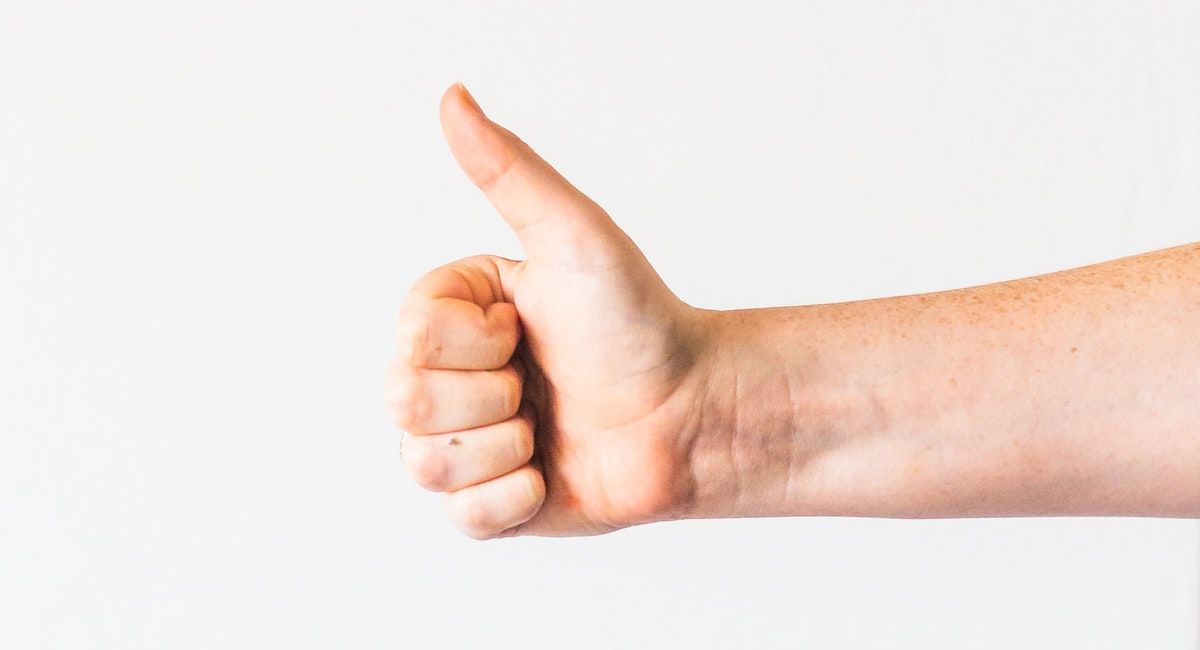 A person giving a thumbs up against a white background