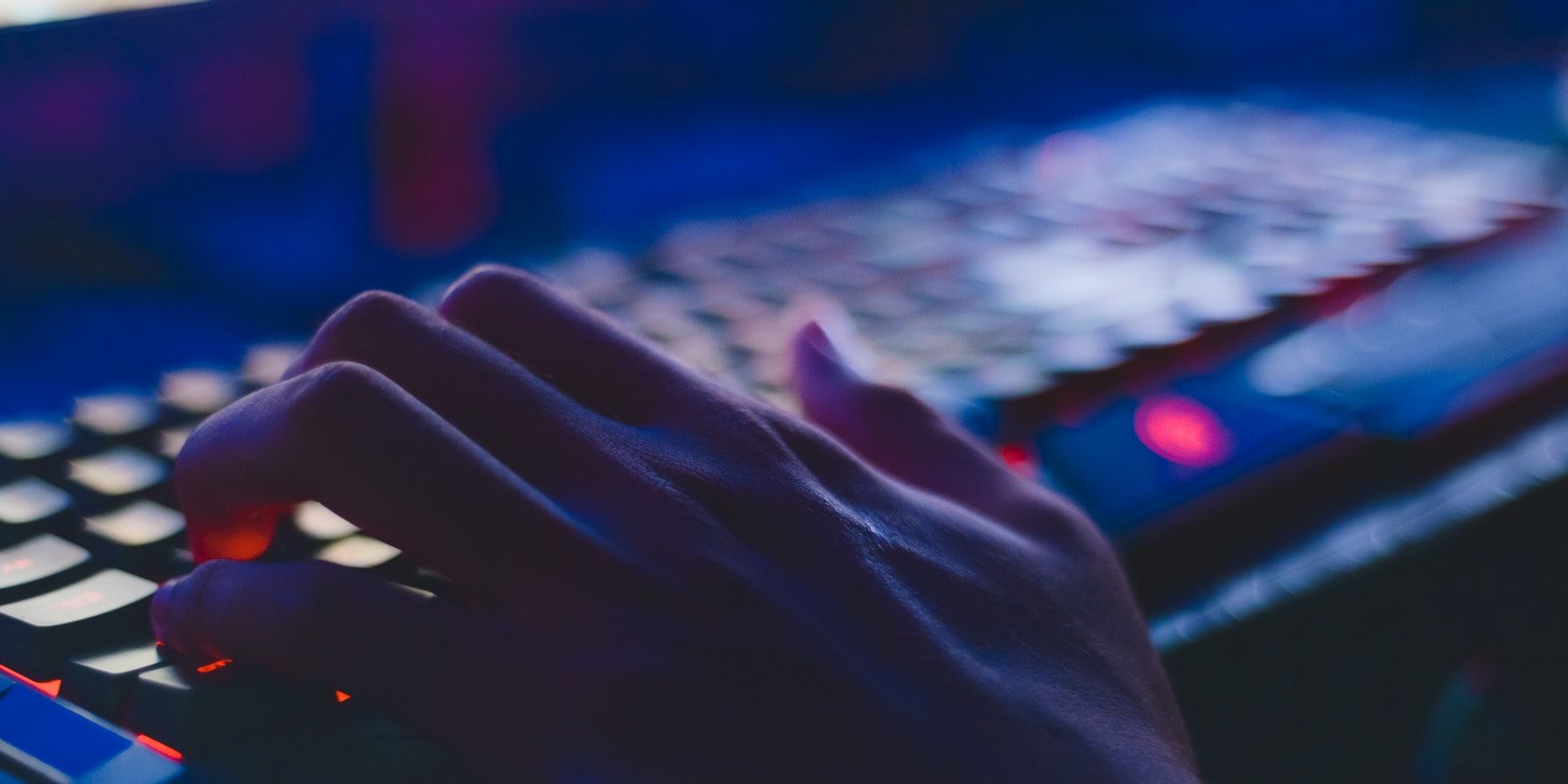 Pexels stock image of a hand typing on a glowing keyboard in the dark