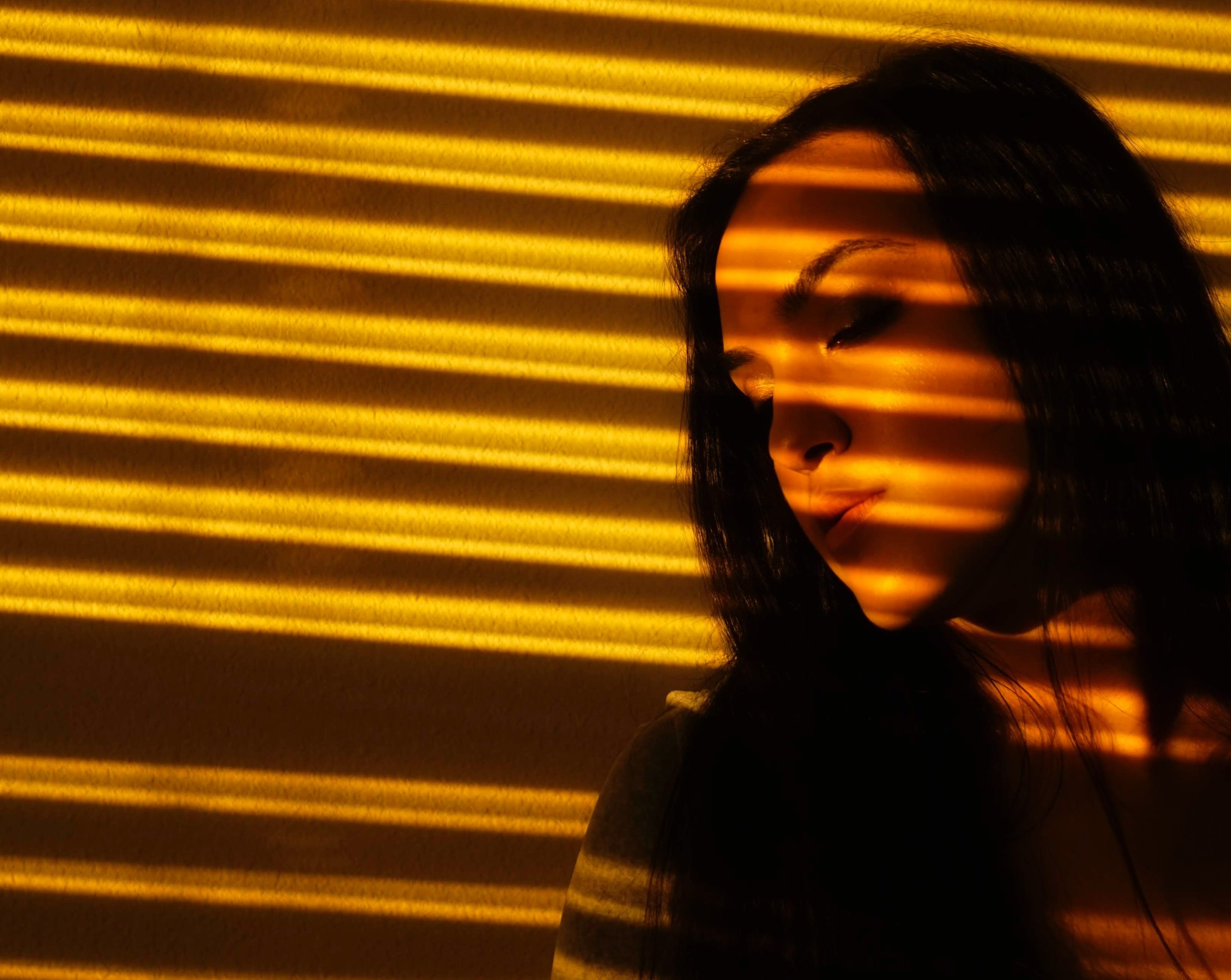 Profile of a woman reflected in the shadow of the blinds