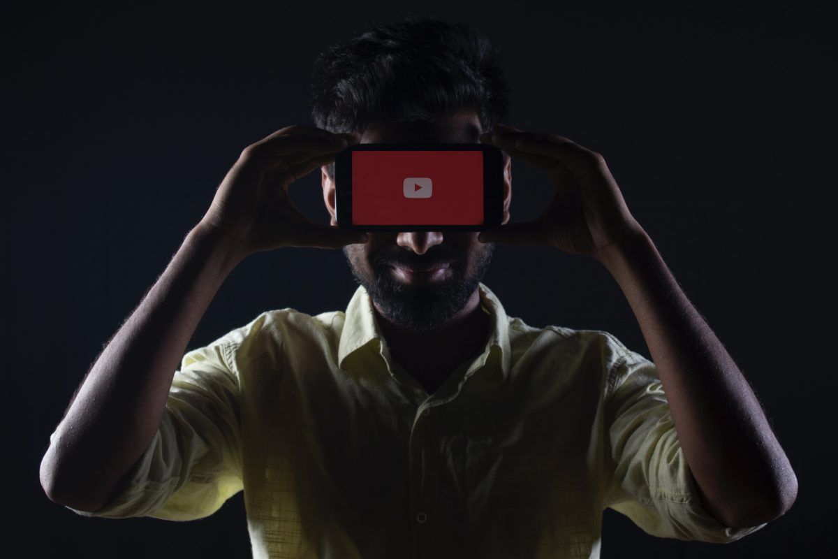 Man holding a phone to his face with the YouTube app open