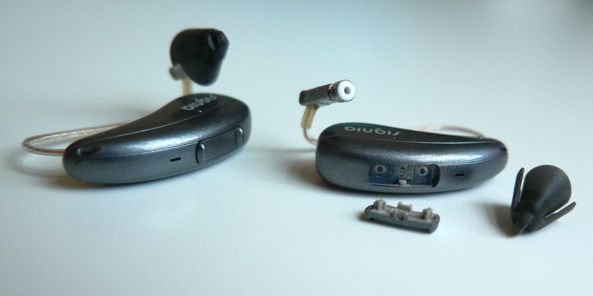 Signia Pure Charge&amp;GO AX hearing aids with rocker switch and eartip removed on one unit.