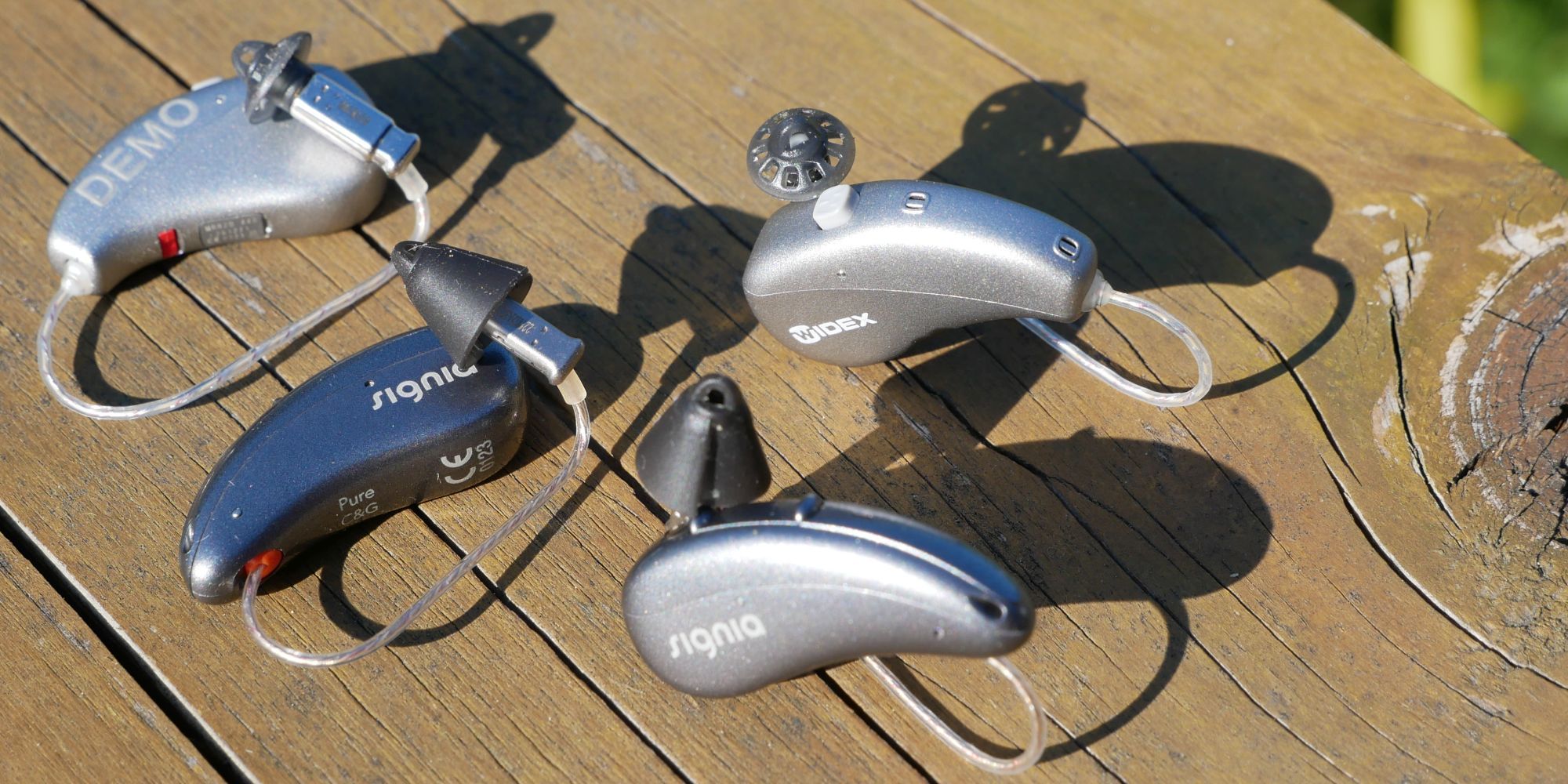 Signia Pure Charge&amp;Go AX next to slightly larger Widex MOMENT hearing aids.