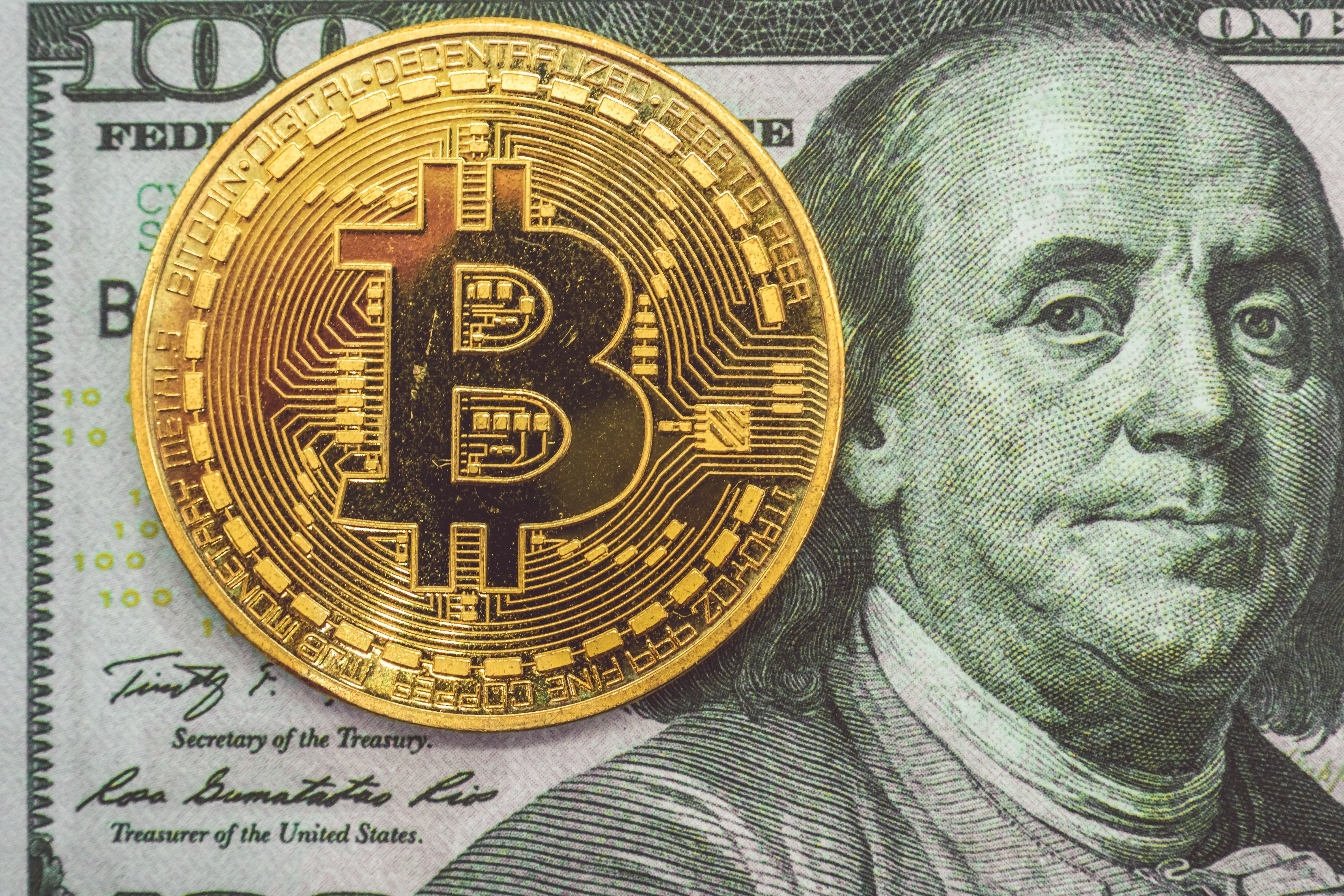 Photo of a Bitcoin next to a USD note