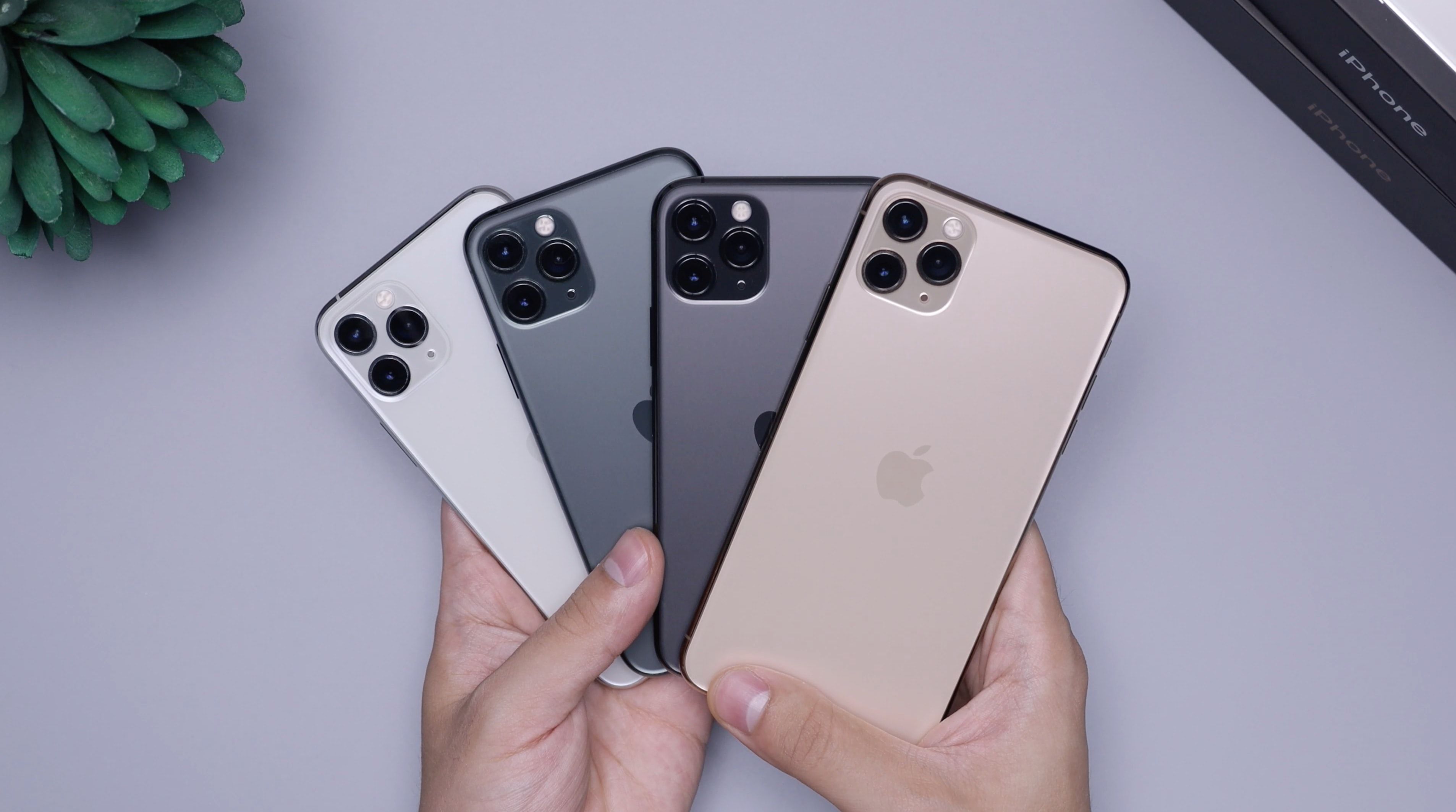 Photo of a person holding numerous iPhone 11 Pro devices