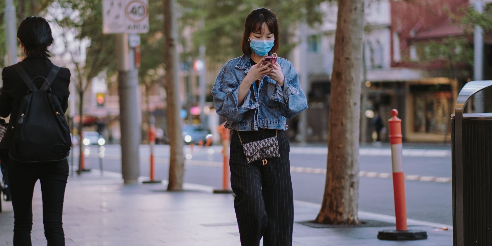 Photo of a woman using her phone while wearing a face mask