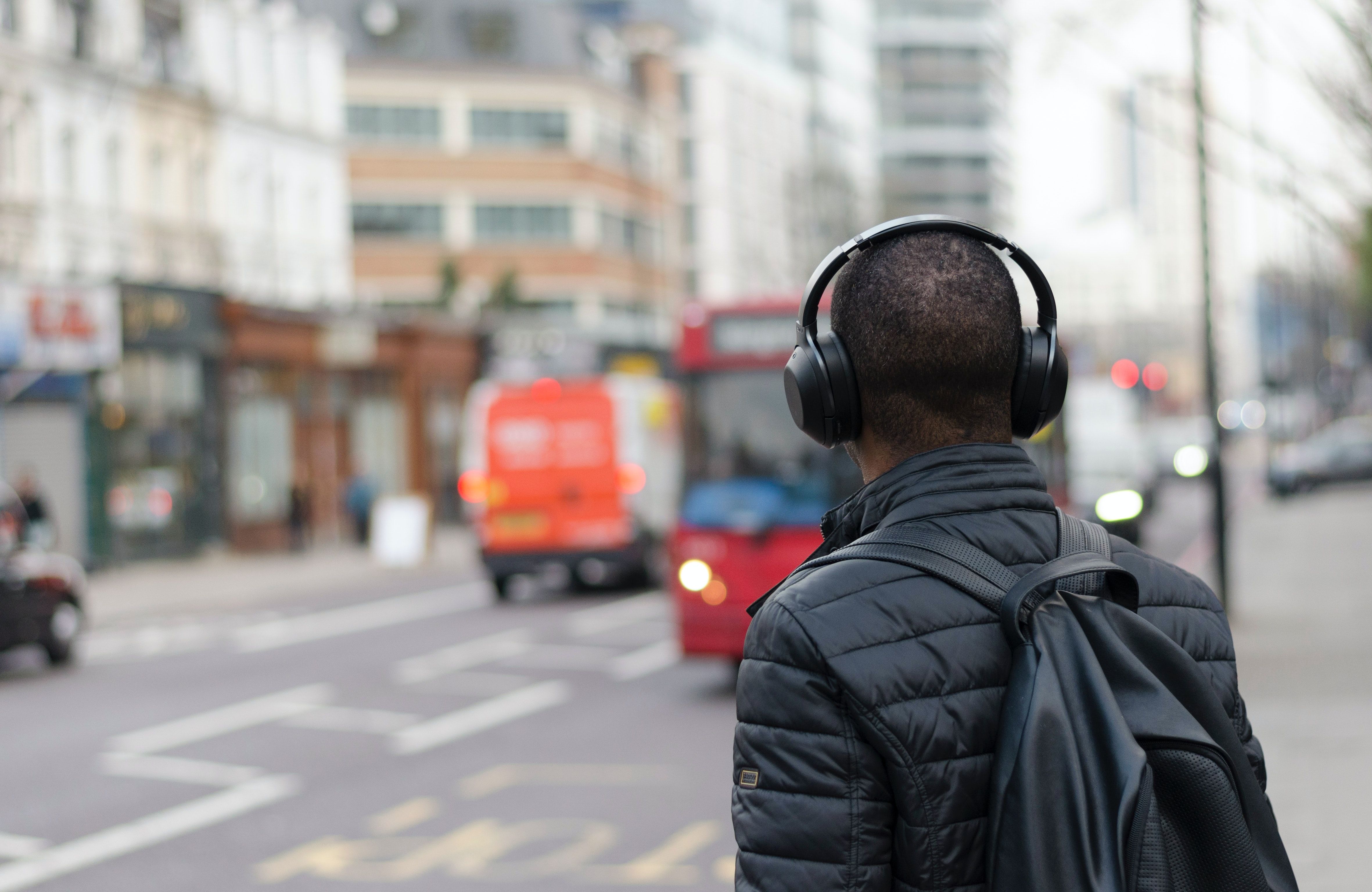 Photo of a person listening to music while waiting for a bus