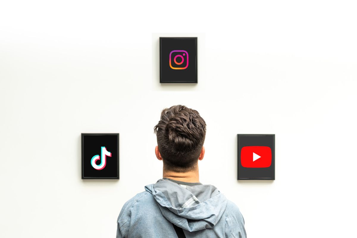 YouTube, Instagram, and TikTok logos mounted on a wall with a man looking at them