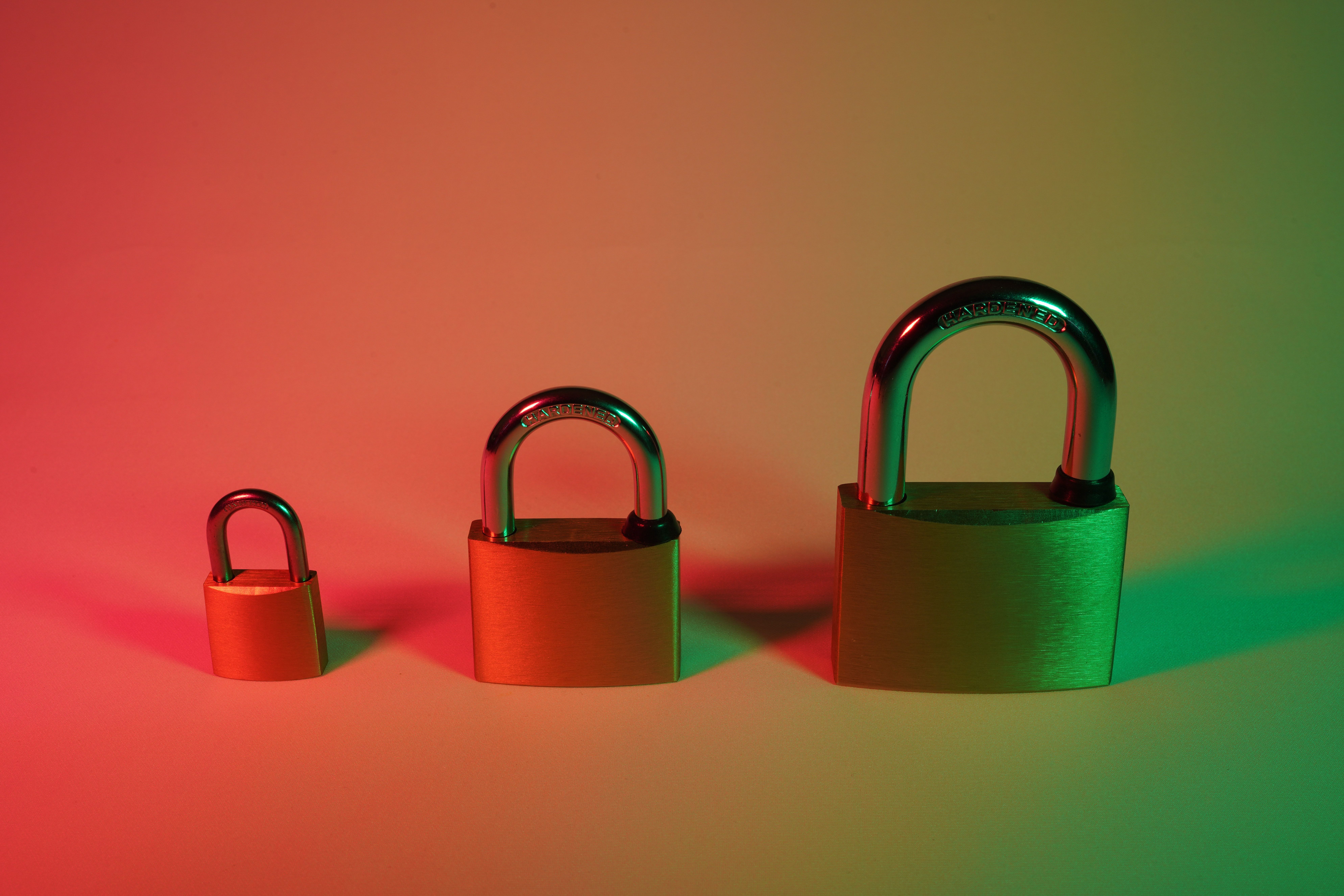 Unsplash stock image of three padlocks - one small, one medium, one large - on a table under red gradient light