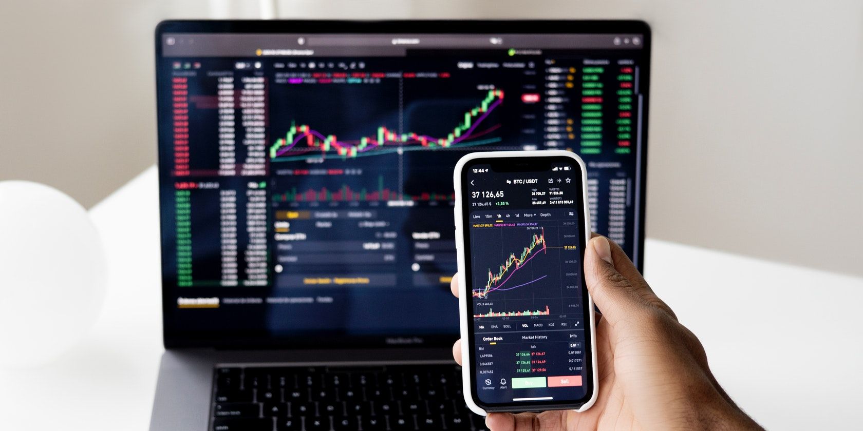 Pexels stock image of a laptop and a smartphone with stock market charts on the screens