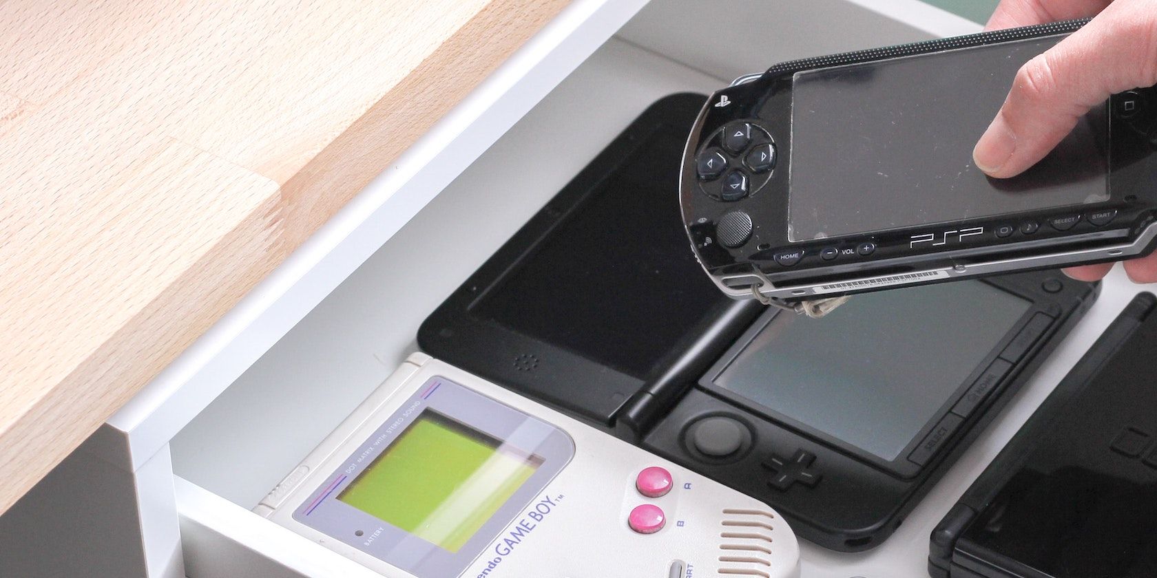 A person putting a PSP in a handheld console drawer