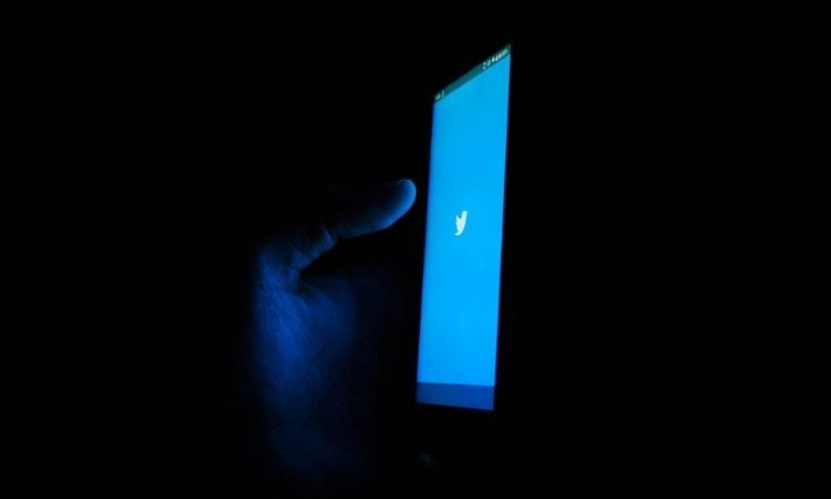 twitter blue screen dark background hand social media