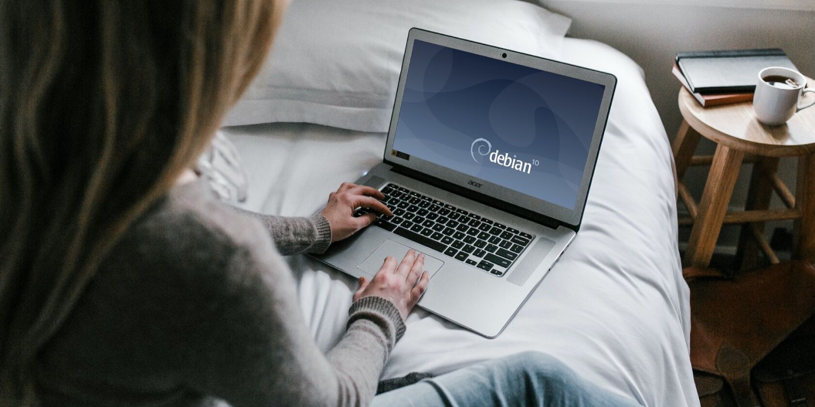 Woman sitting on bed using laptop with Debian