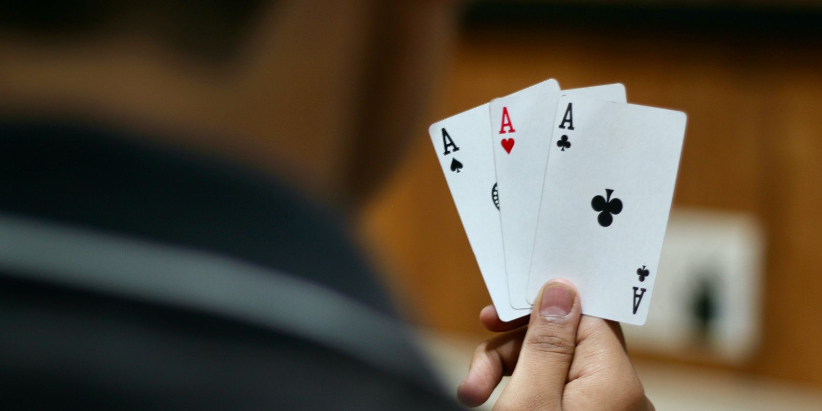 A hand holding three aces