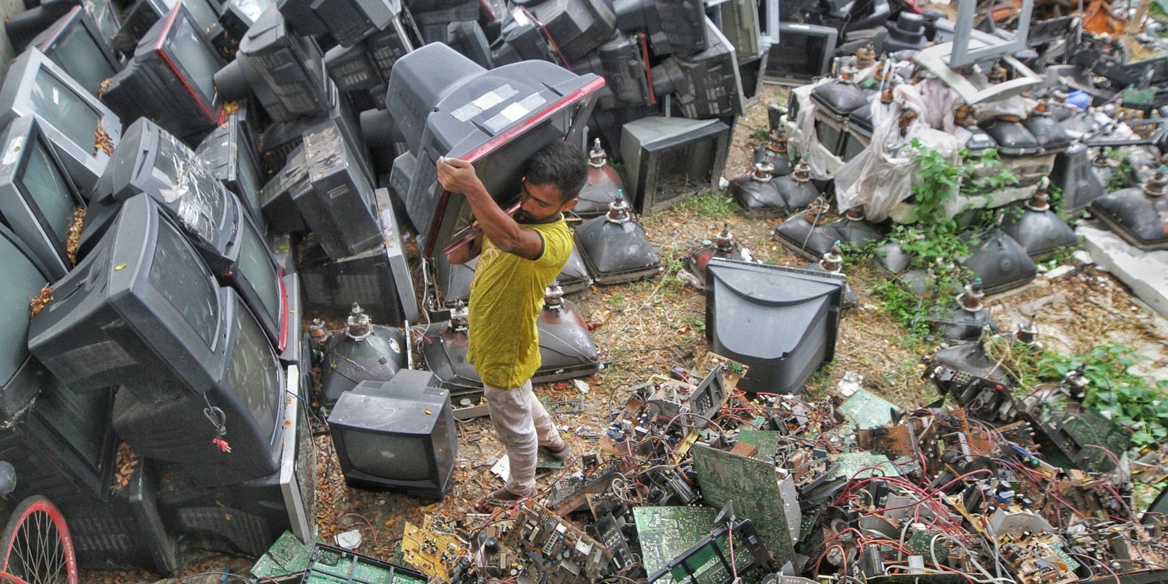 Man lifting an old TV in an e-waste dumpsite