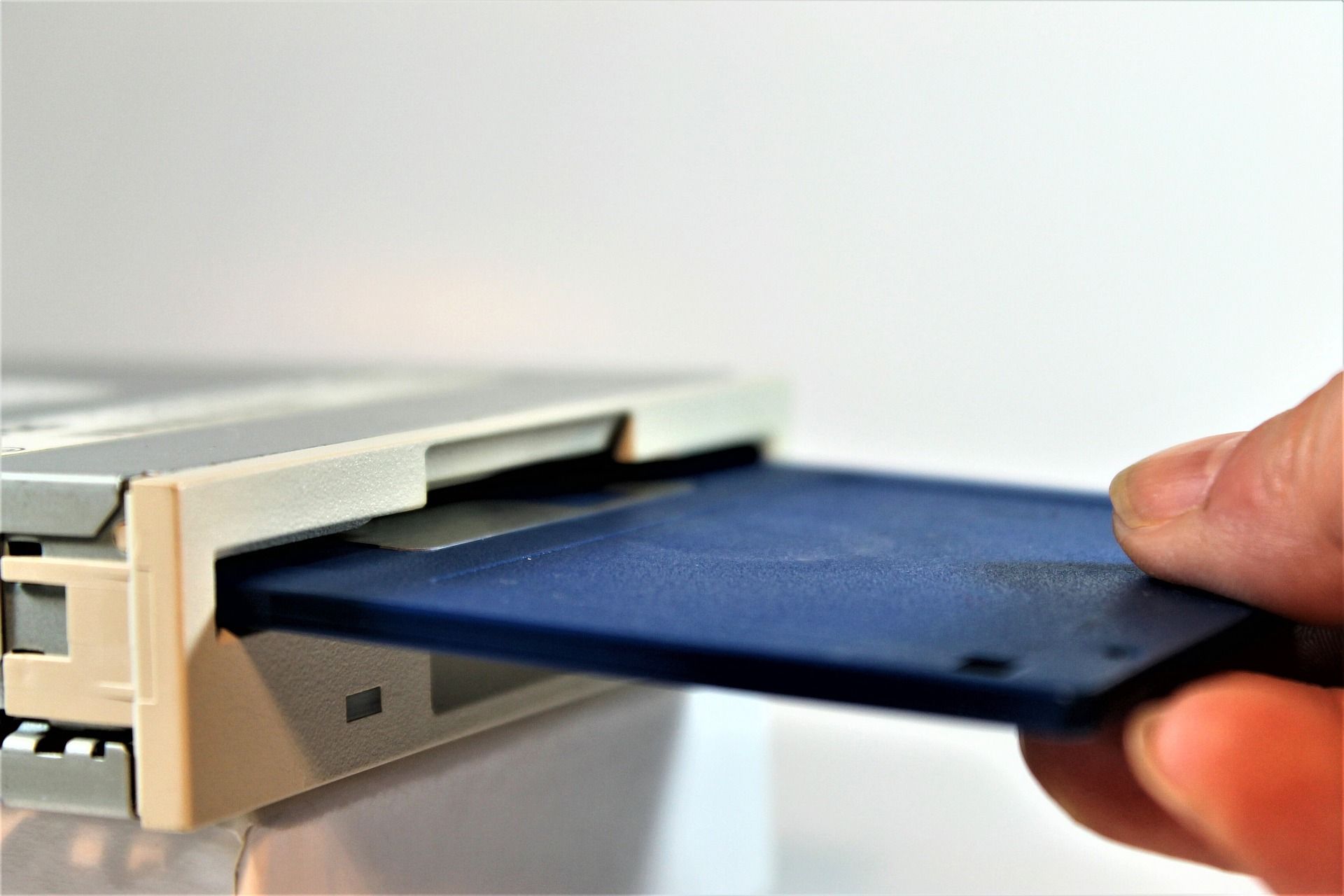 Blue Floppy Disk being inserted into drive with white background