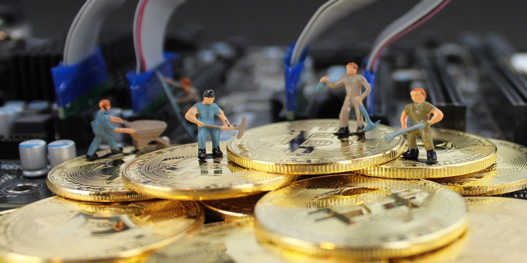 miniature models of workers standing on Bitcoin