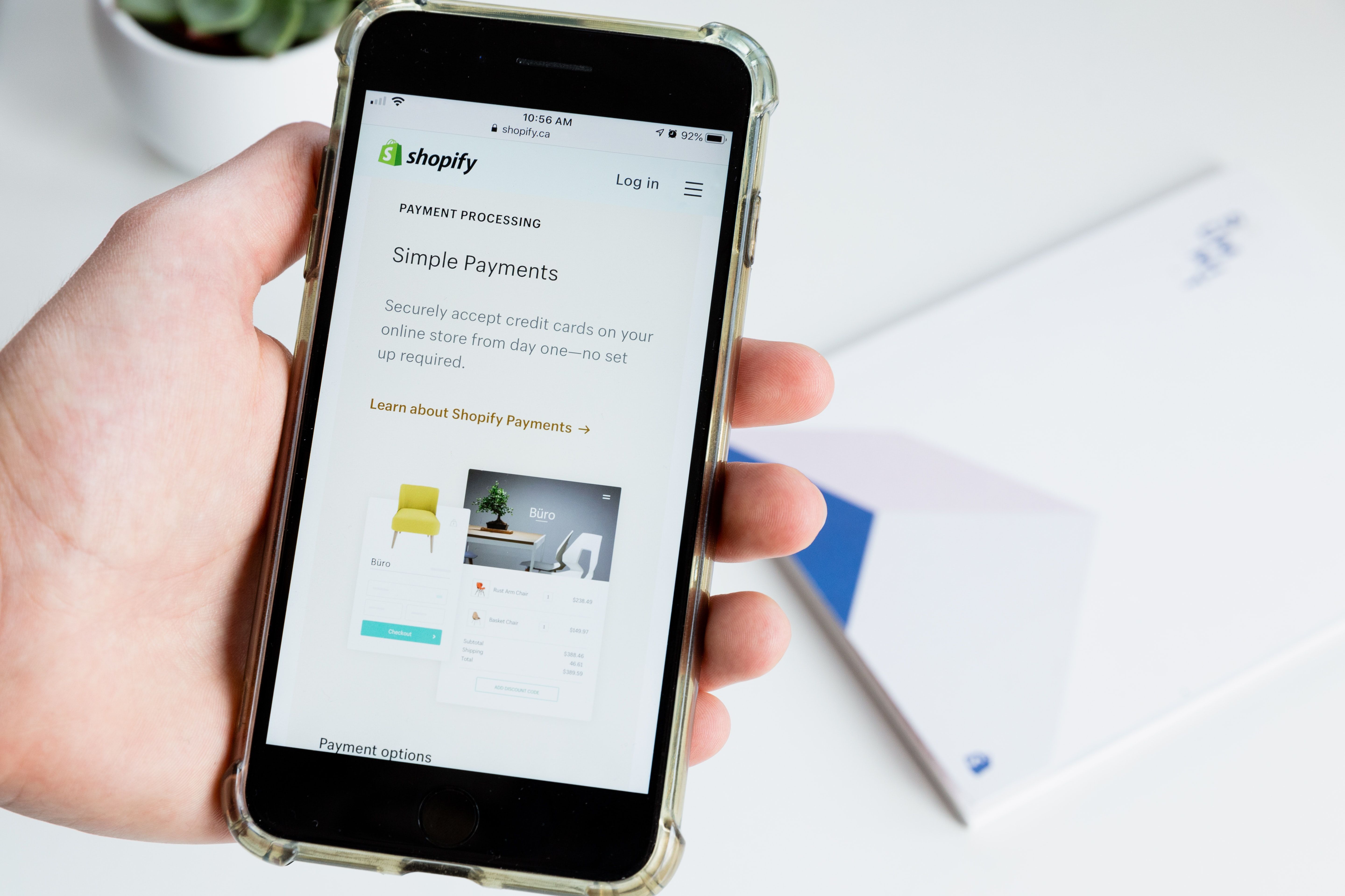 Photo of a person holding their phone on a Shopify page