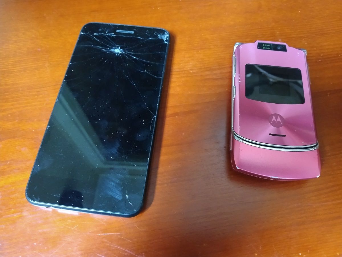 A broken smart phone next to a flip phone