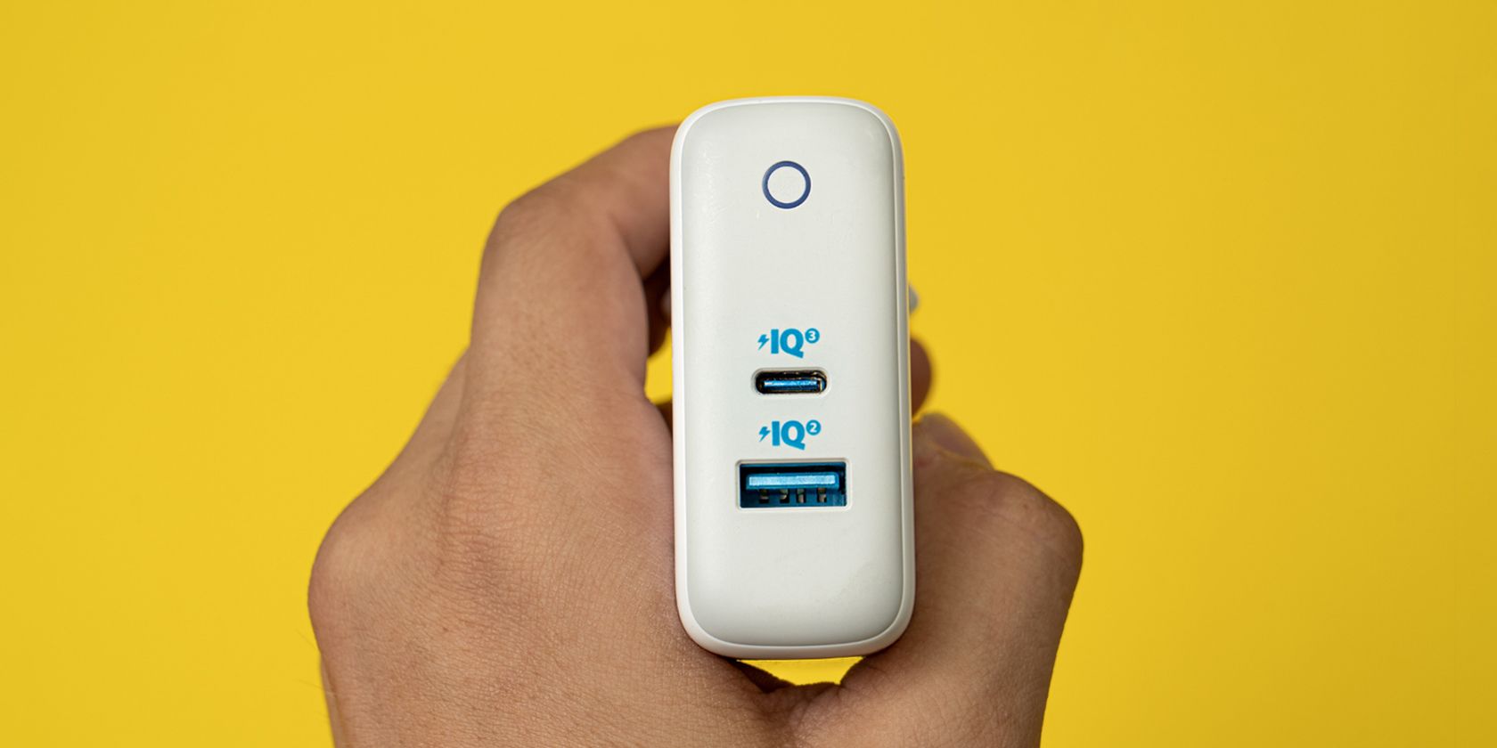 GaN charger held by a hand on a yellow background