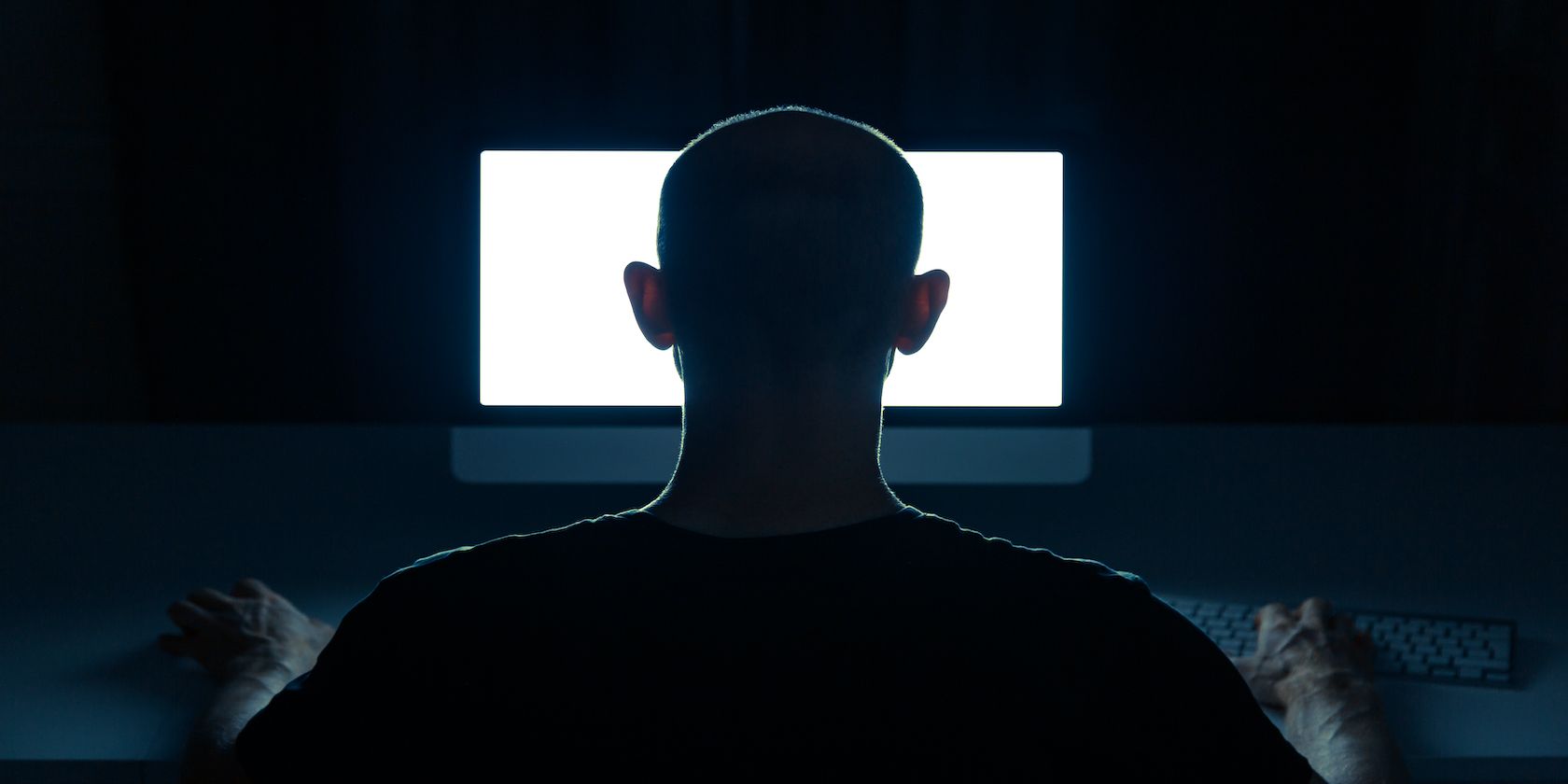 Man sitting in front of a computer screen in the dark