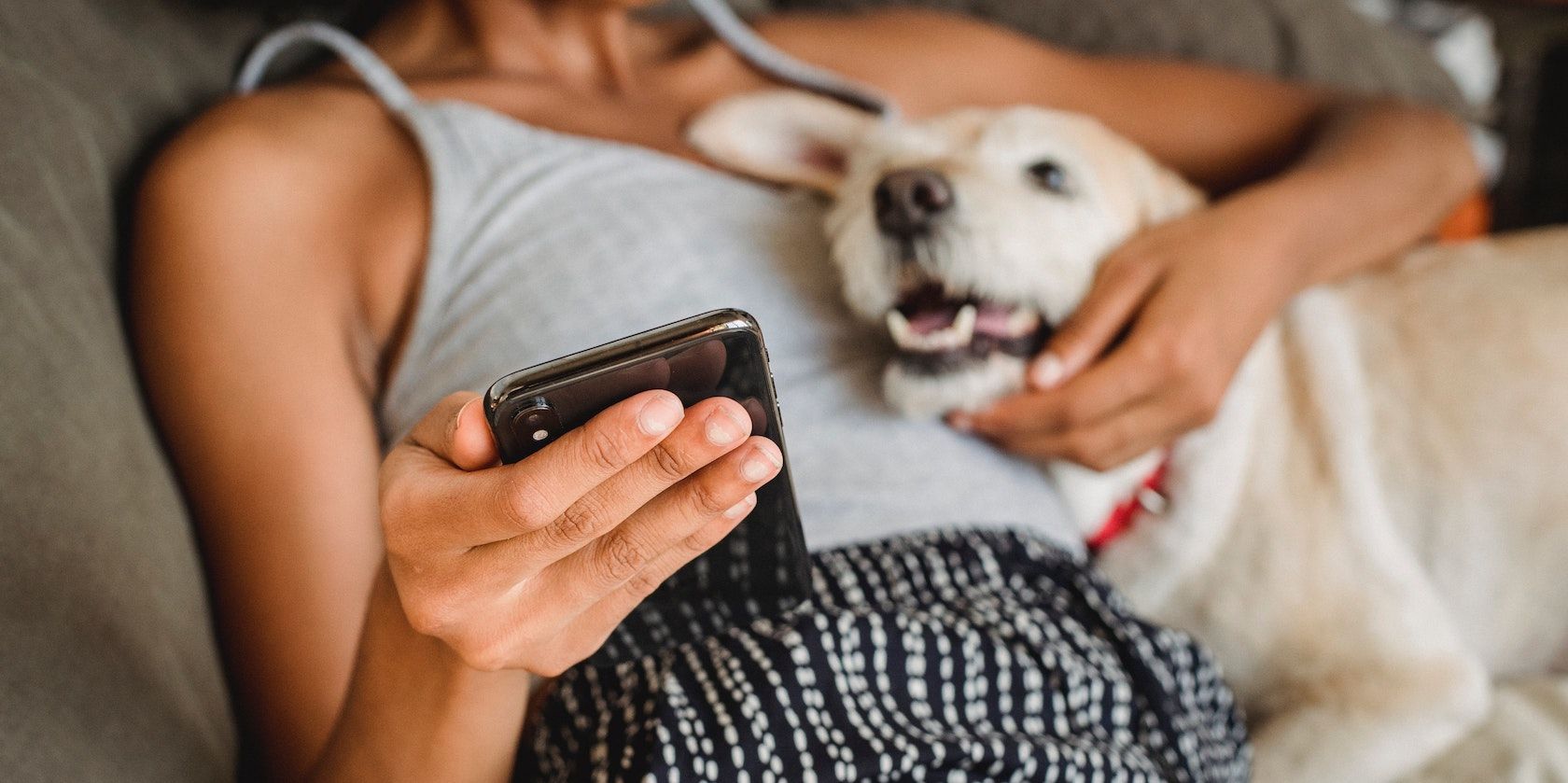 woman on phone and dog cuddling 