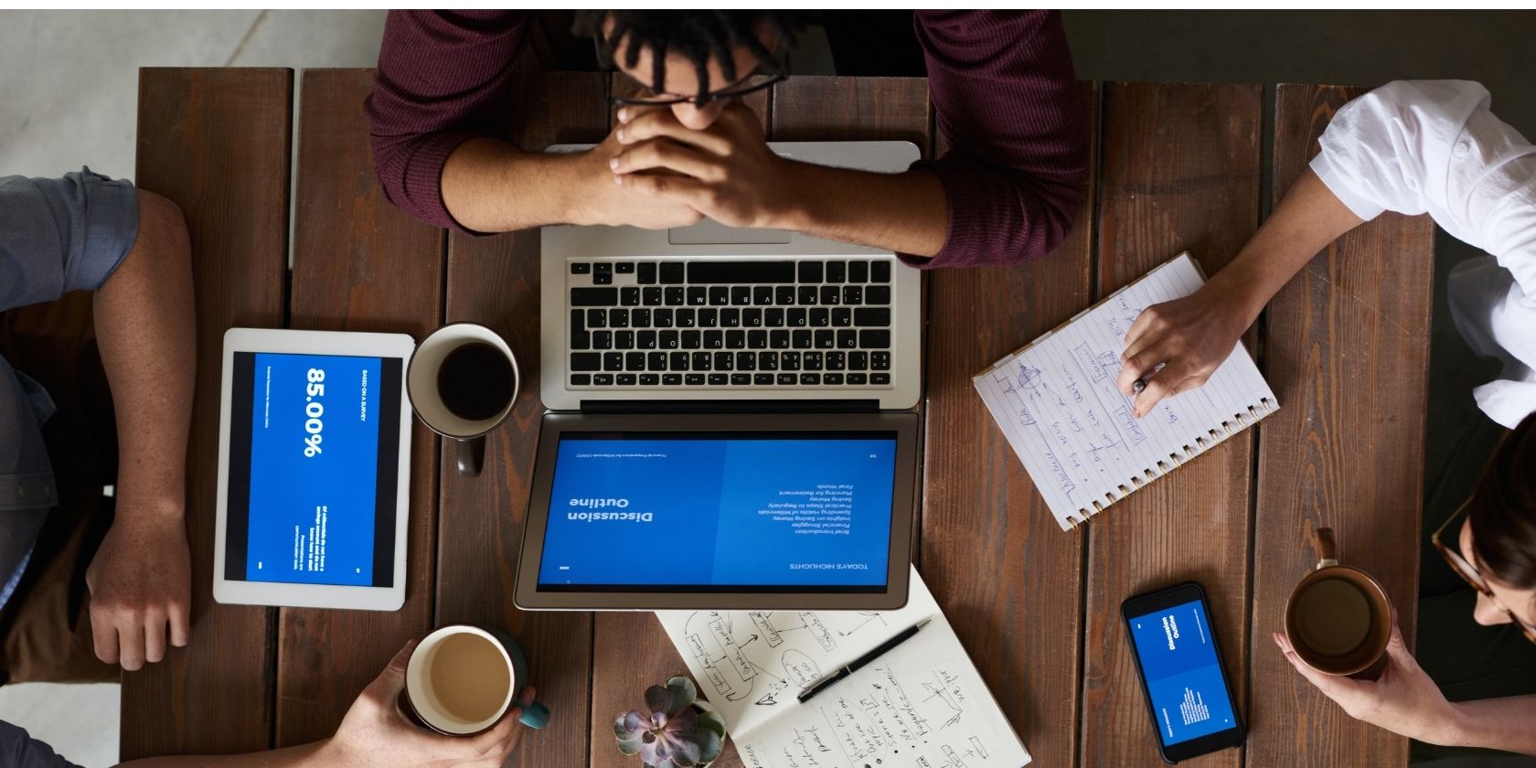 People with Apple Devices on a Table Sharing a File