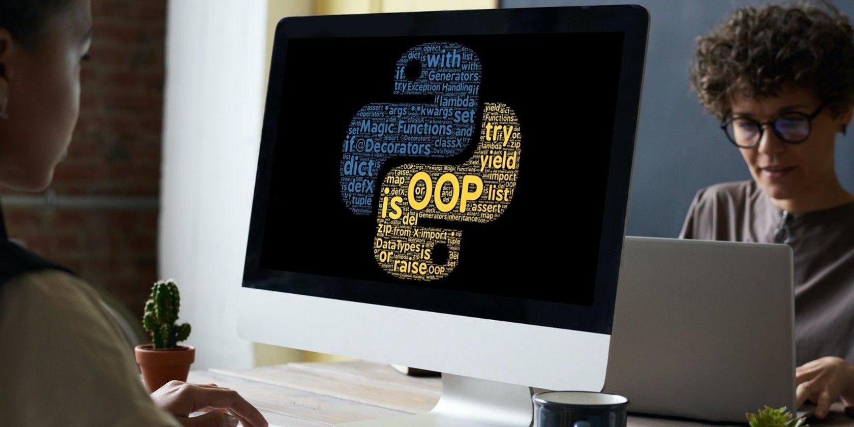 Two women sitting facing each other with Python's logo showing on the front computer screen