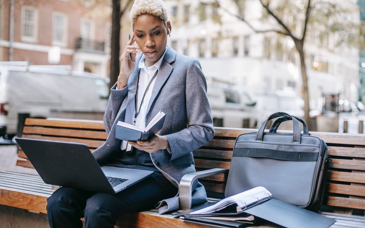 A woman working on a laptop and reading a book