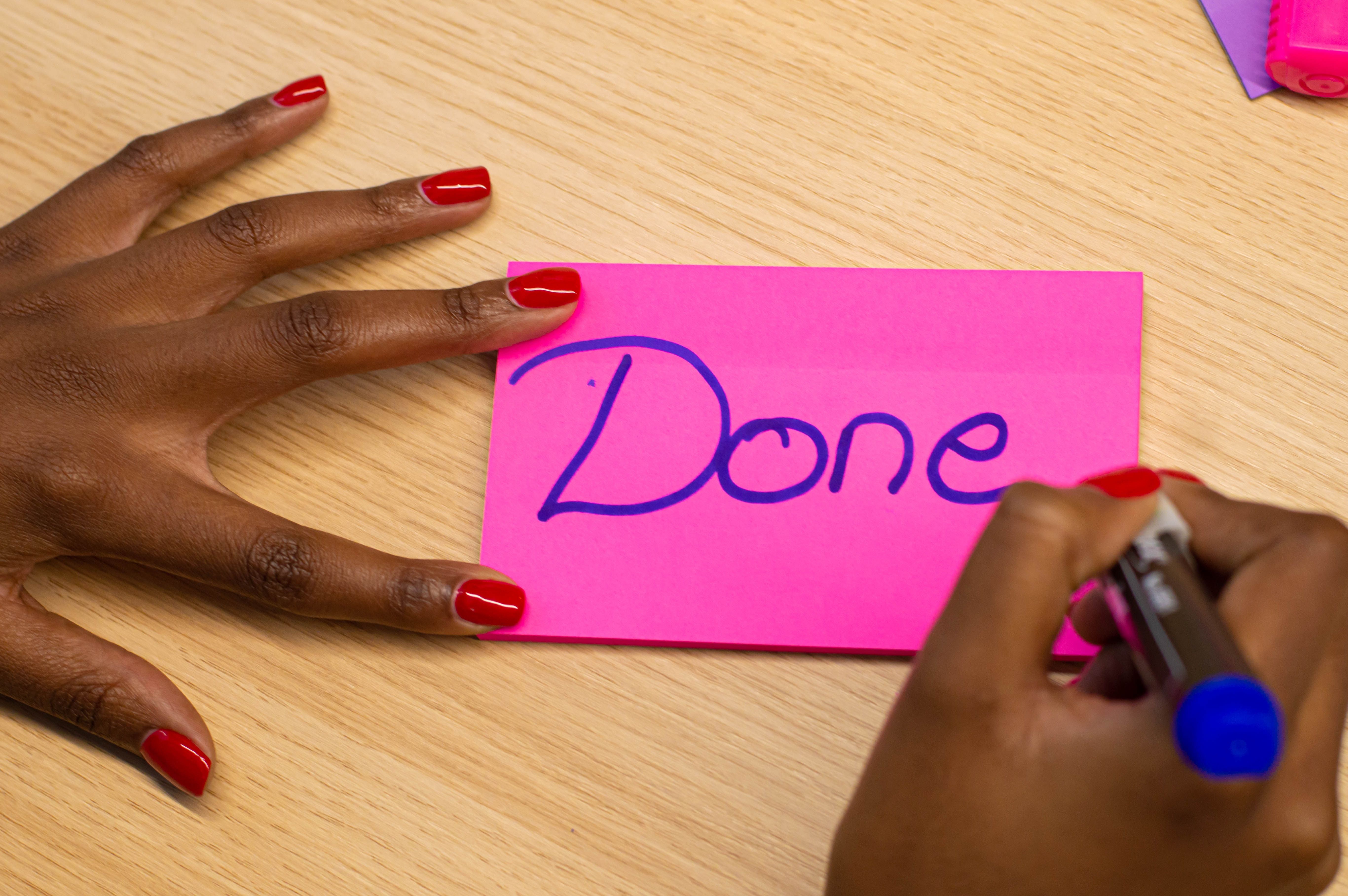 Person writing "done" on a post it note