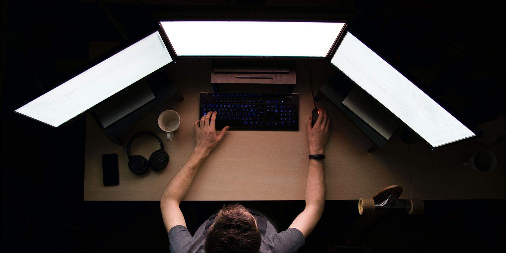 man facing three computer screens - Che cos’è Microsoft Garage e cosa può fare per te?