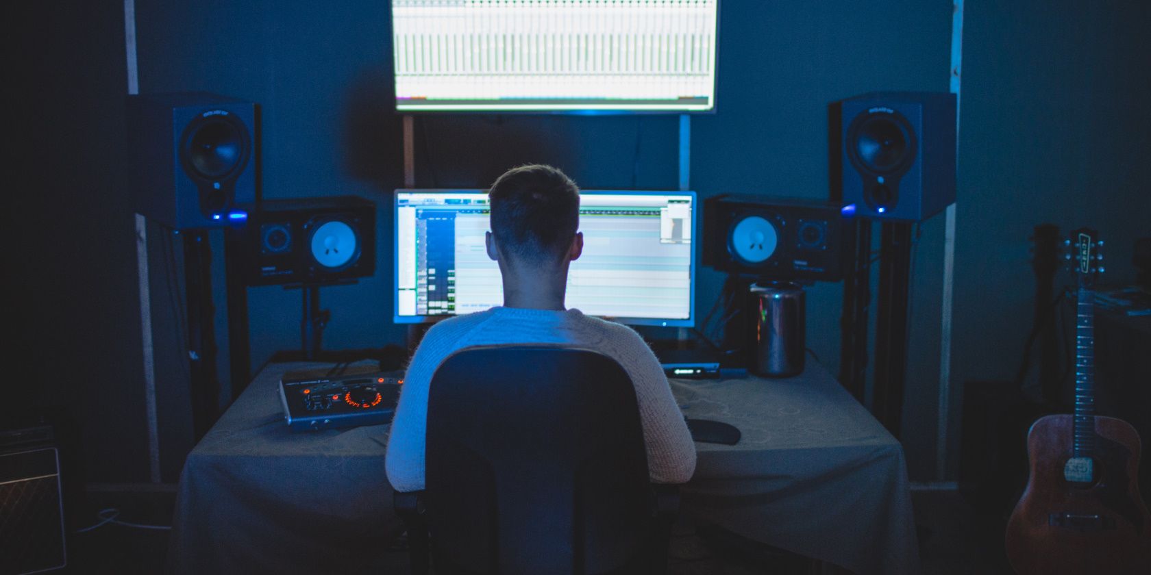 man sitting in front of speakers and mixing desk