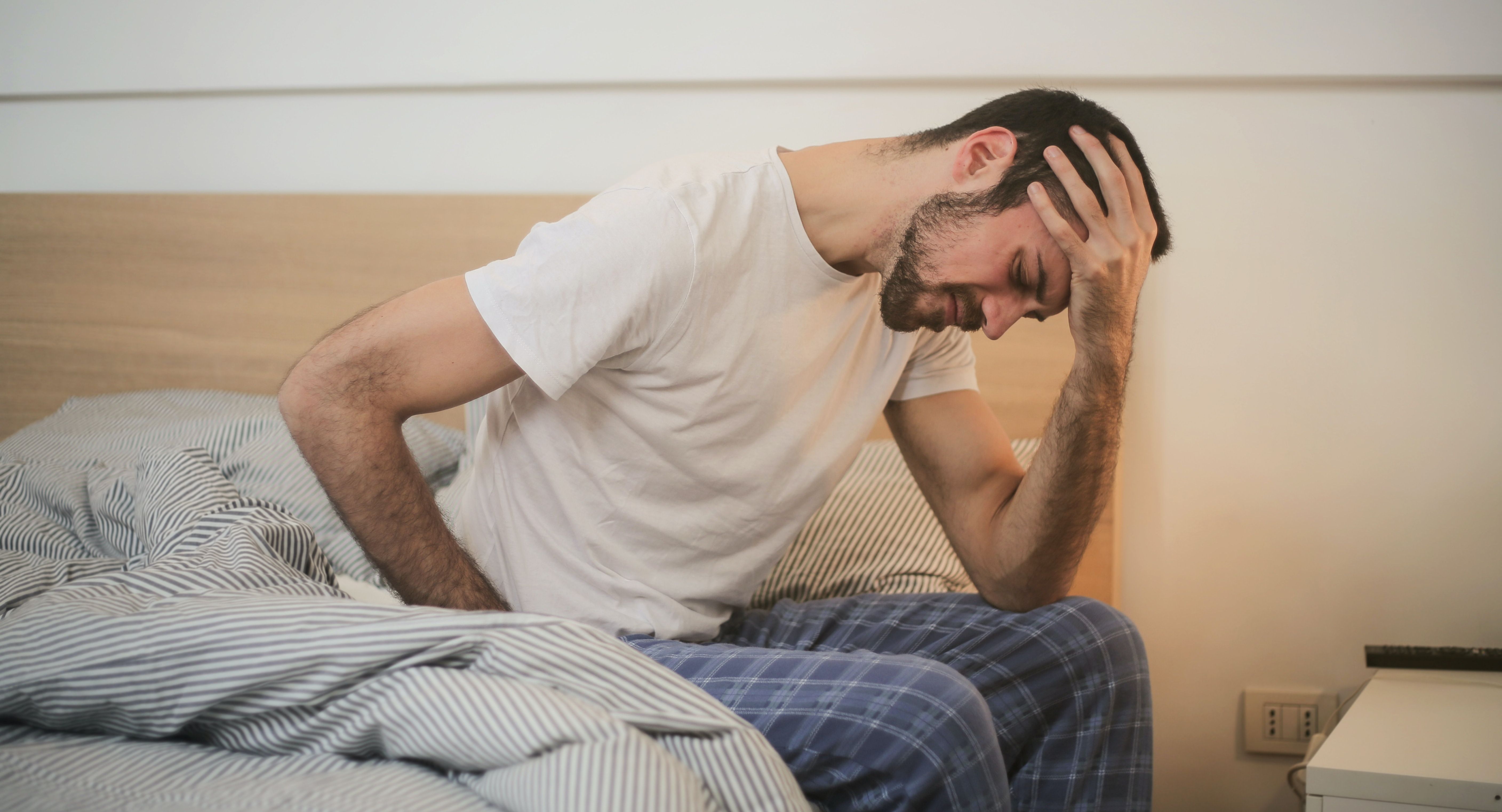 man in bed with headache