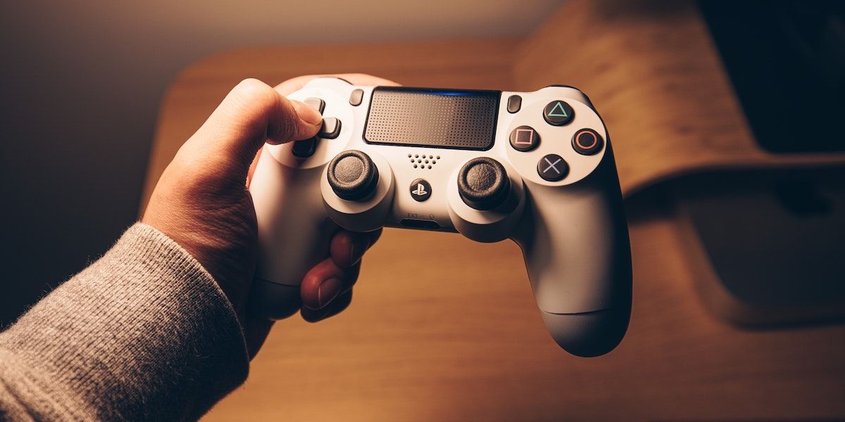 A person holding a white PS4 controller