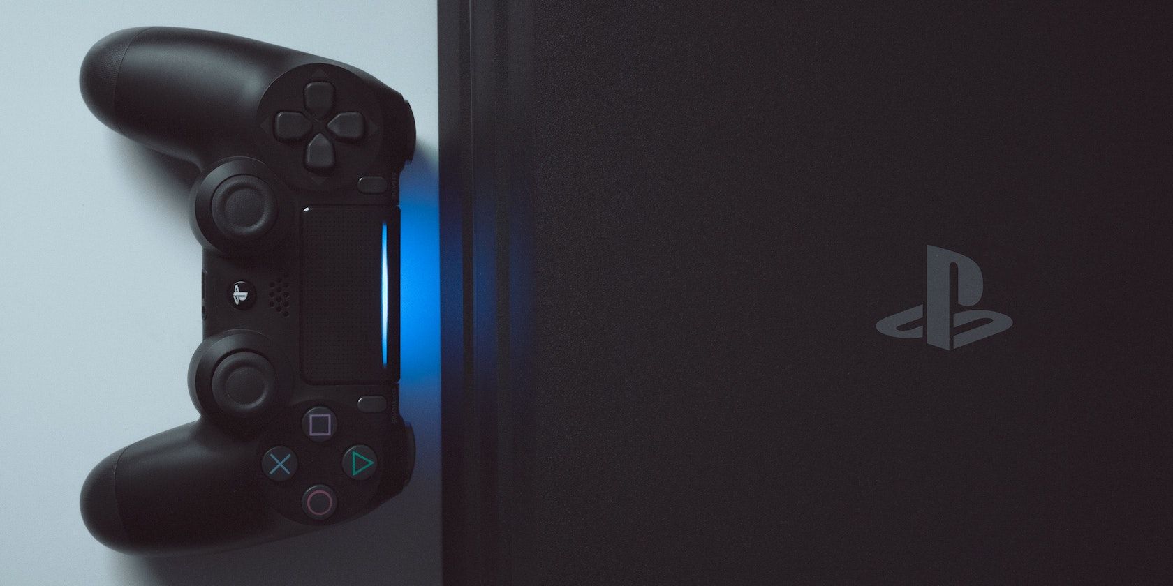 A PS4 console and controller emitting a blue light