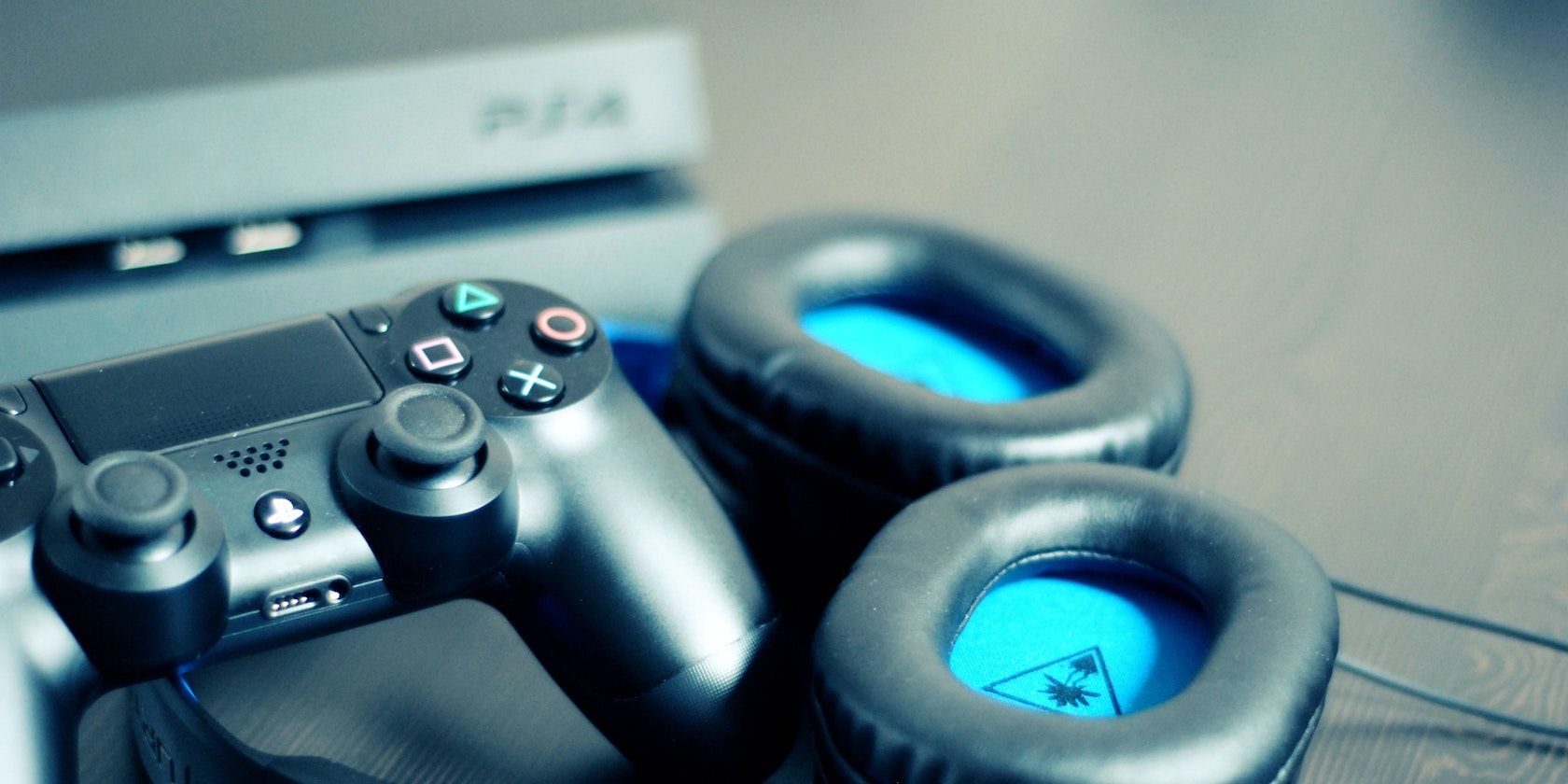 A PS4 with a controller and blue headphones