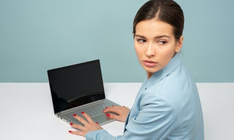 woman in blue on a laptop looking suspiciously