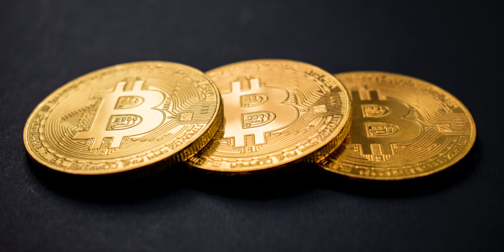 three bitcoins laying on black background